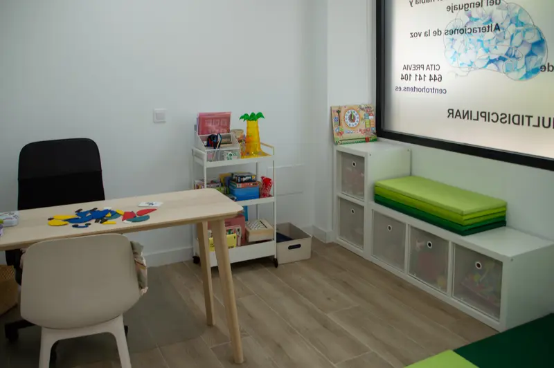 Sala de terapia infantil con material de juego, colchonetas y mesa de trabajo